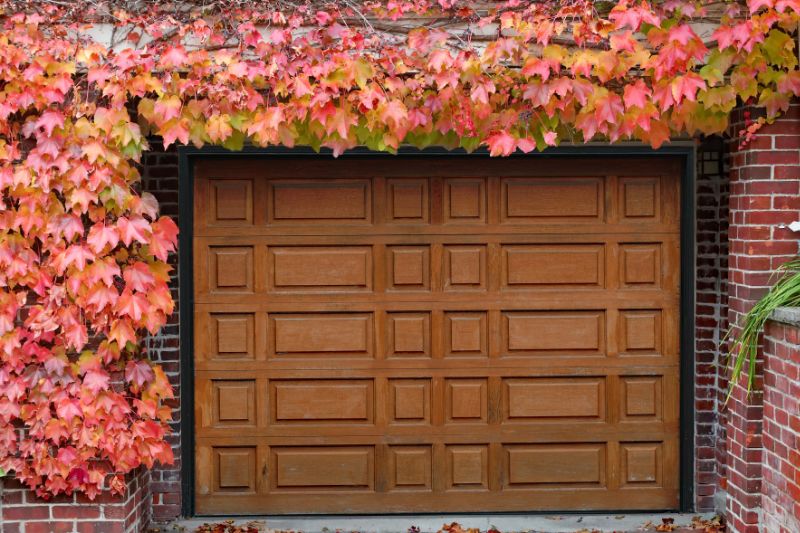 Wooden garage door surrounded by fall leaves